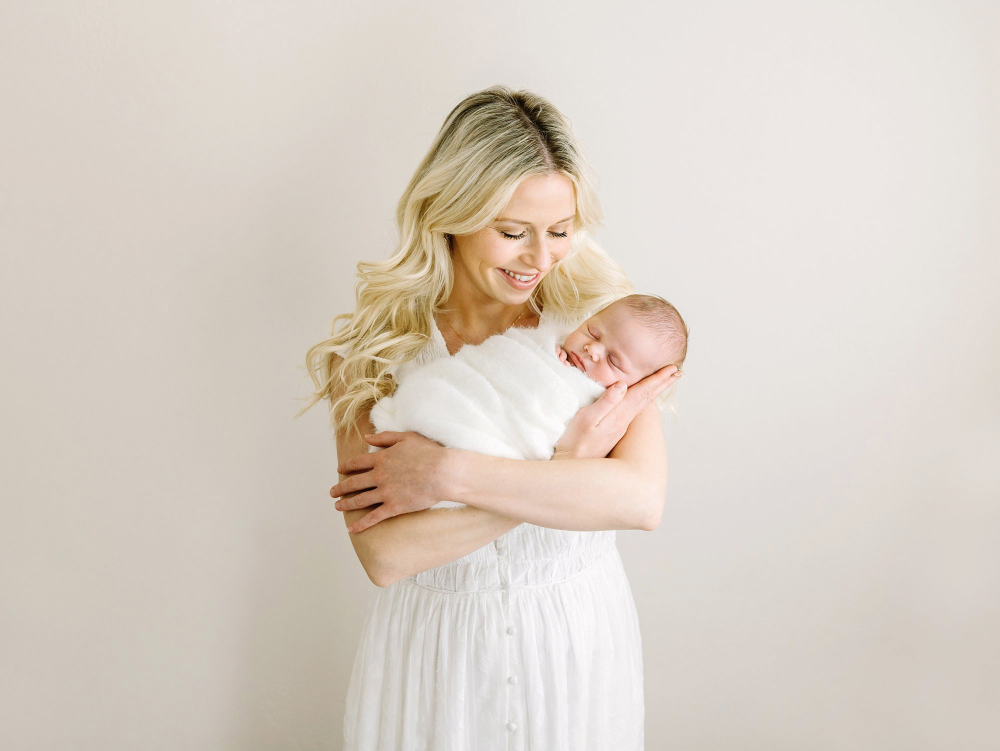 A new mom smiles down at her brand new baby during her photo session with Camarillo newborn photographer Daniele Rose