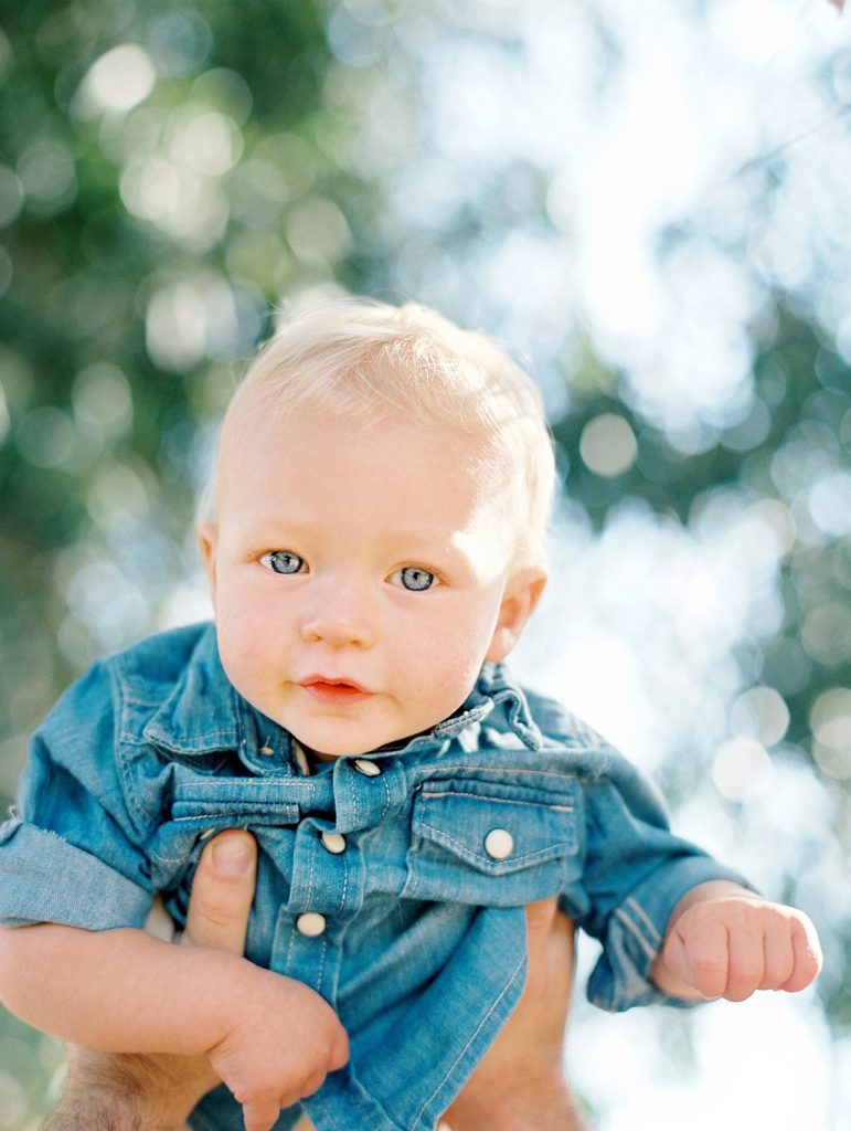 A blue eyed one year old baby looks into the camera during a family portrait session in Camarillo, California