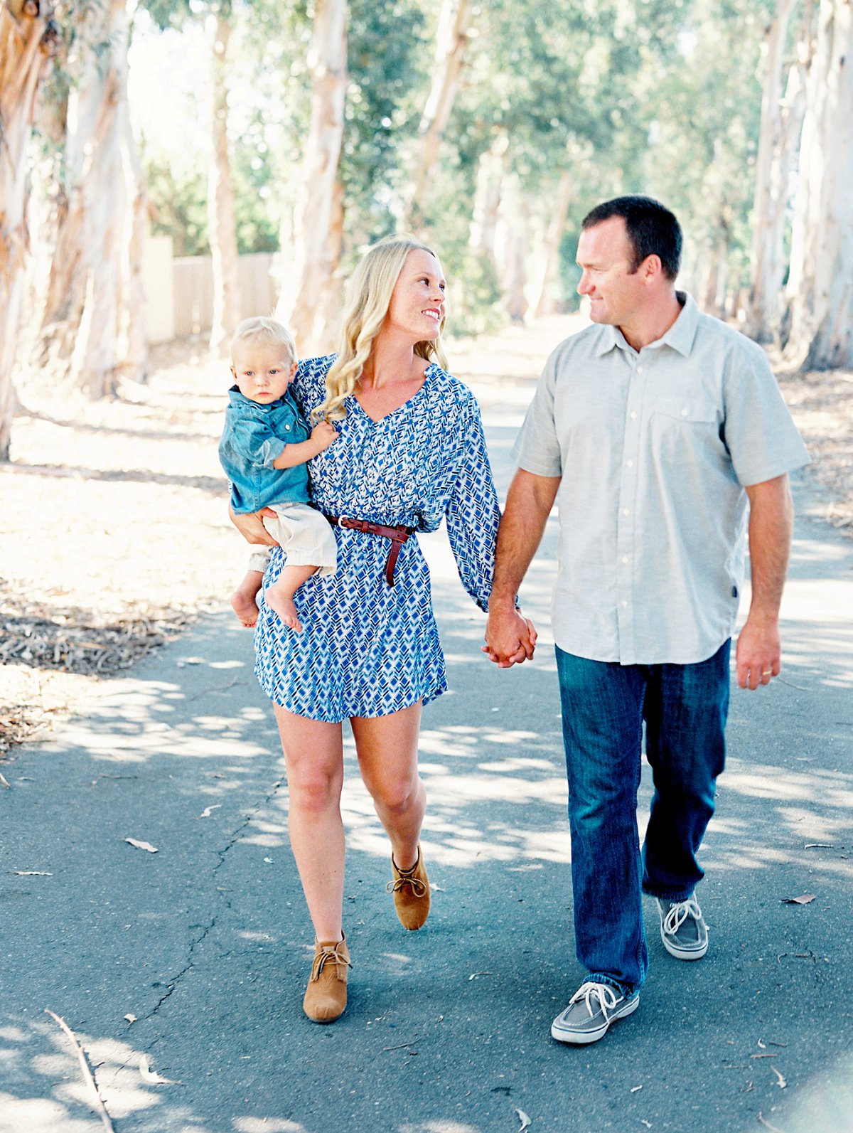 Photo of a family walking down a tree lined pathway holding hands during their Camarillo family portrait session