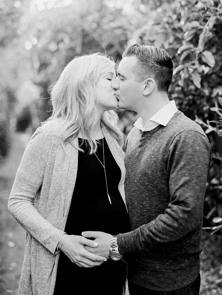 Black and white image of expectant parents kissing during their maternity portraits in Santa Barbara