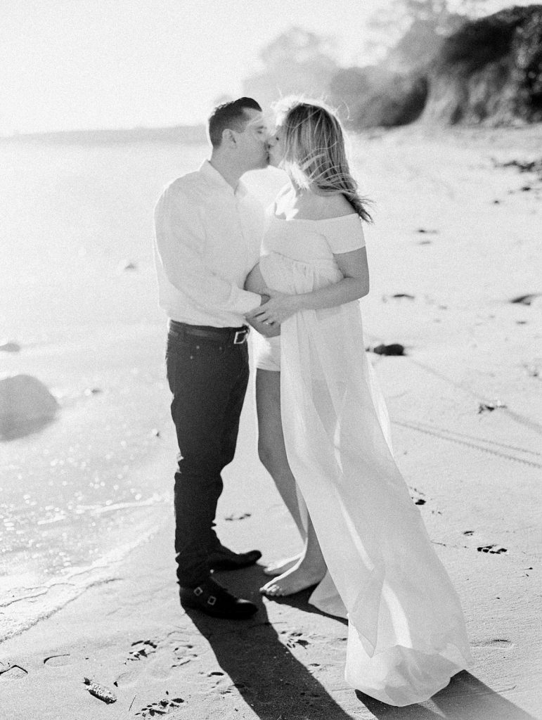Black and white film image of a couple kissing during their maternity session
