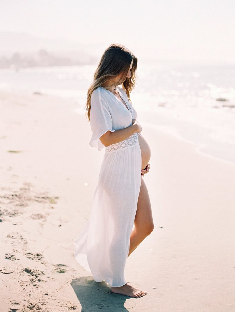 A woman walks on the beach in Santa Barbara during a maternity portrait session at Hammond's Beach