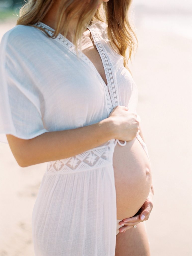 An image of a pregnant women's belly during a beach maternity session