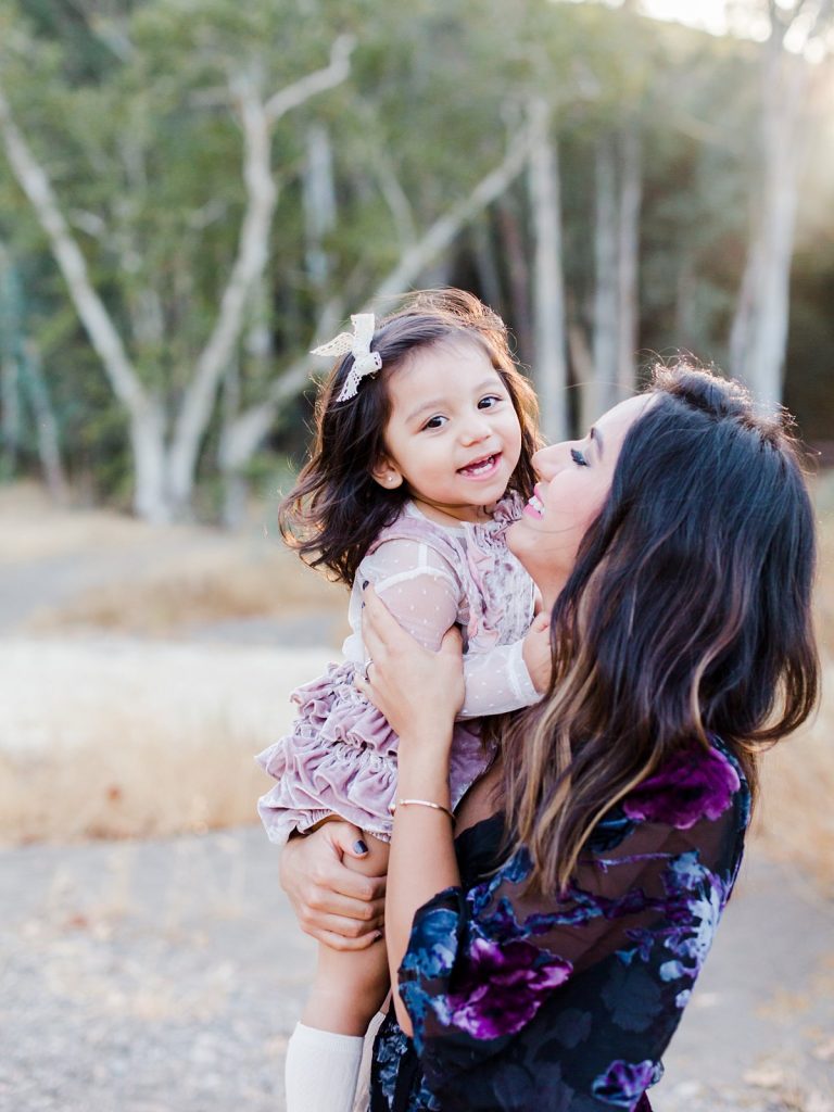 A giggling young girl being held by her mother during family portraits in Thousand Oaks, California