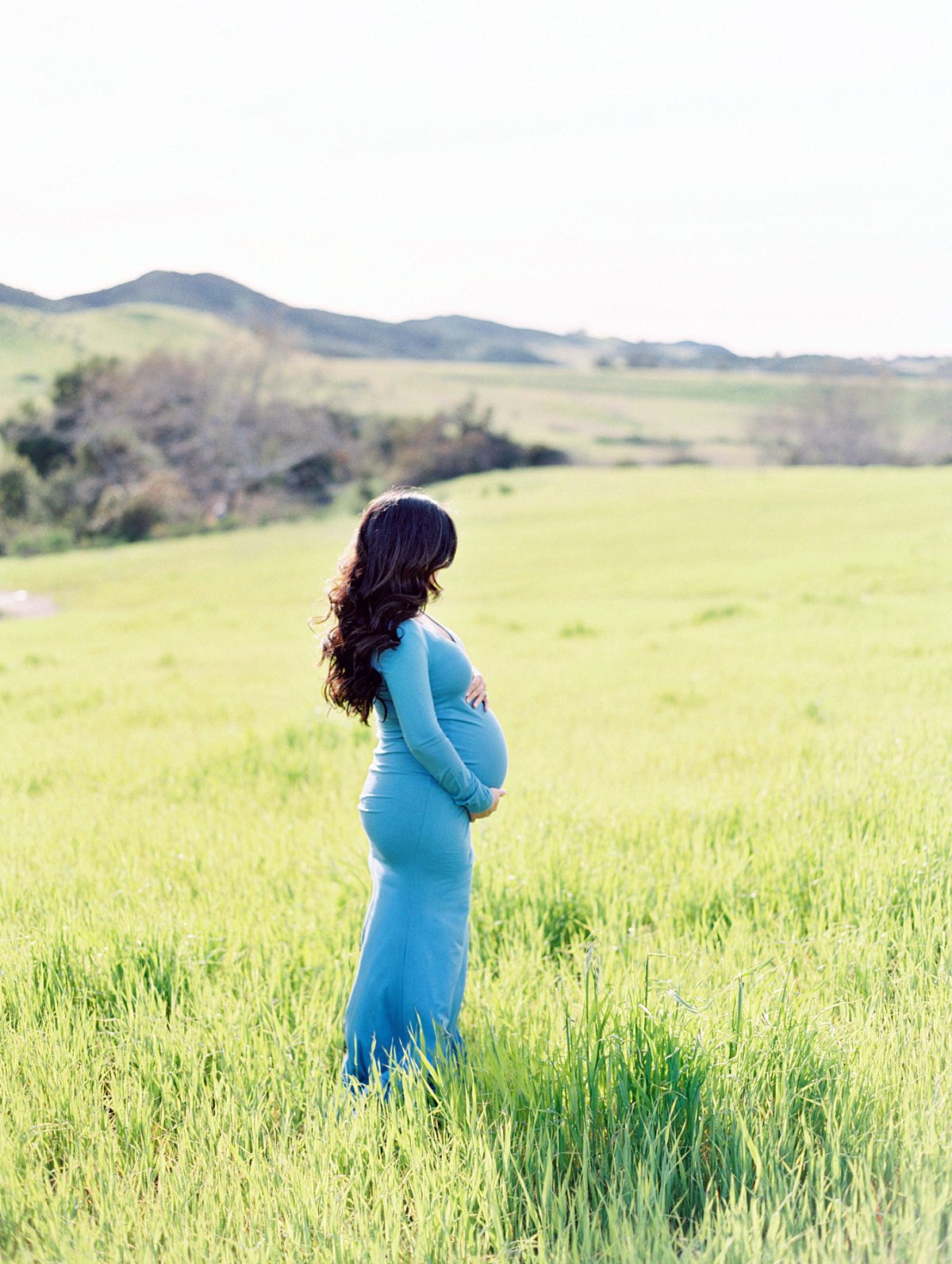 Thousand Oaks maternity photographer Daniele Rose captures an expectant mother wearing a blue dress in a field of green grass