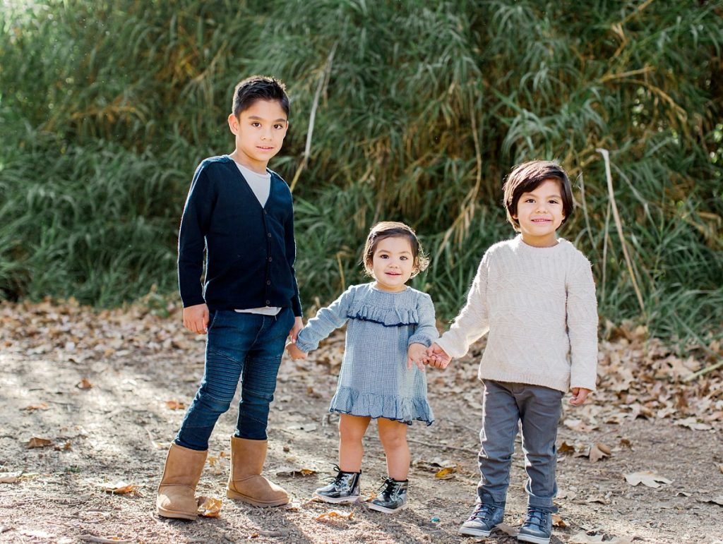 Siblings hold hands and play during family photos in Ventura County