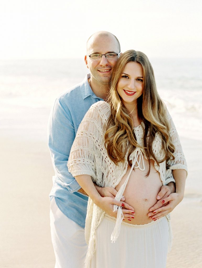 Expectant parents smile at the camera during their Ventura maternity session