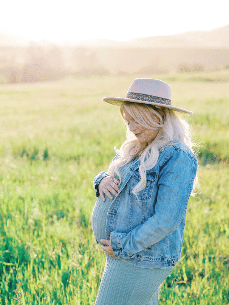 An expectant mother in a sunlit green field during her spring maternity session with Thousand Oaks photographer Daniele Rose