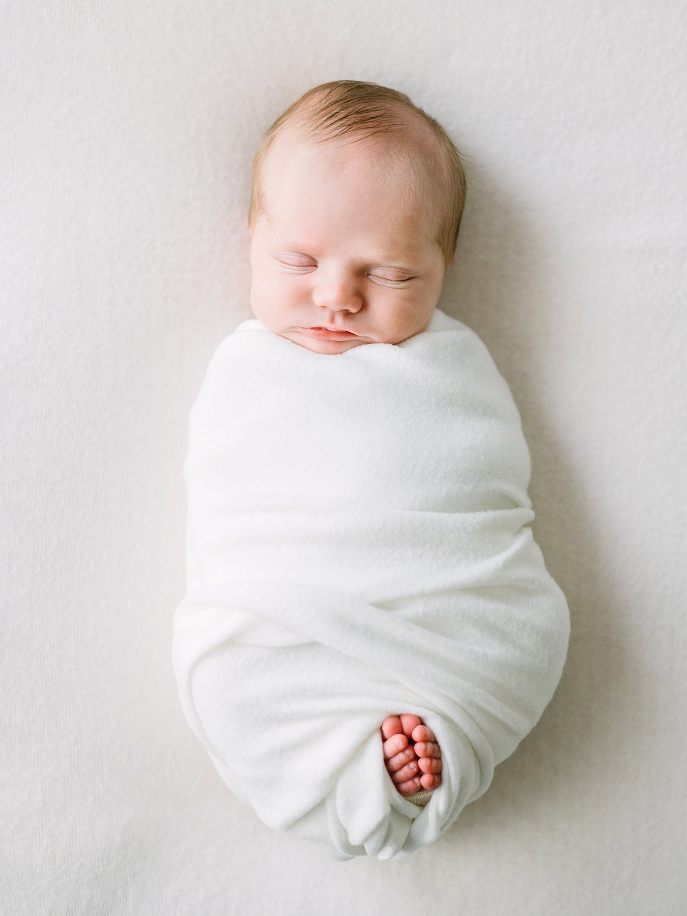 A newborn baby in a white swaddle photographed by Thousand Oaks newborn Photographer, Daniele Rose.