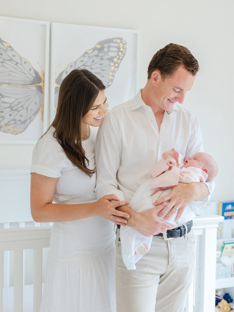 New parents look at their baby lovingly during their lifestyle newborn photography session.