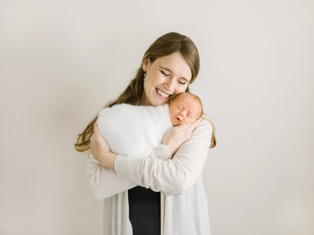 A new mom snuggles with her newborn baby during a newborn session in photographer Daniele Rose's natural light studio.