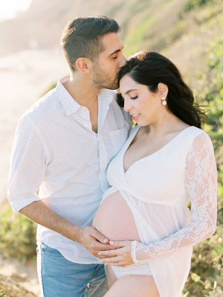 A couple snuggling on the beach during their maternity session in Los Angeles.