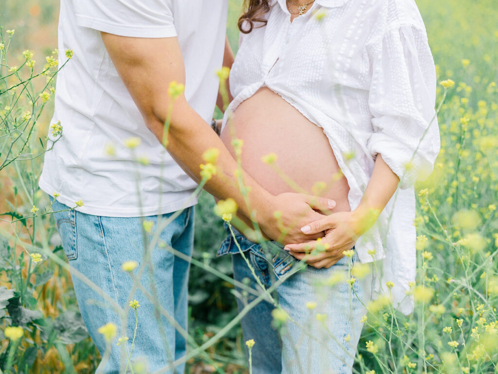 Expecting parents cradling baby bump in yellow wildflowers in the Ojai Meadow Preserve