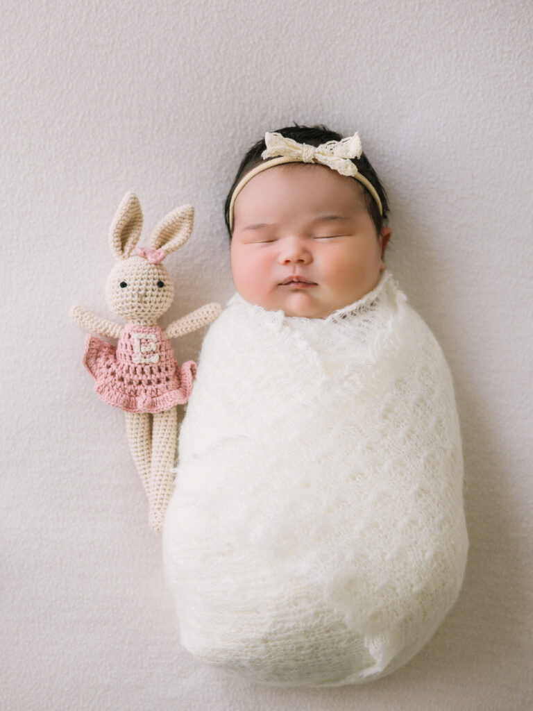 Swaddled newborn with sentimental stuffed bunny heirloom showing must-have newborn photos with meaningful items