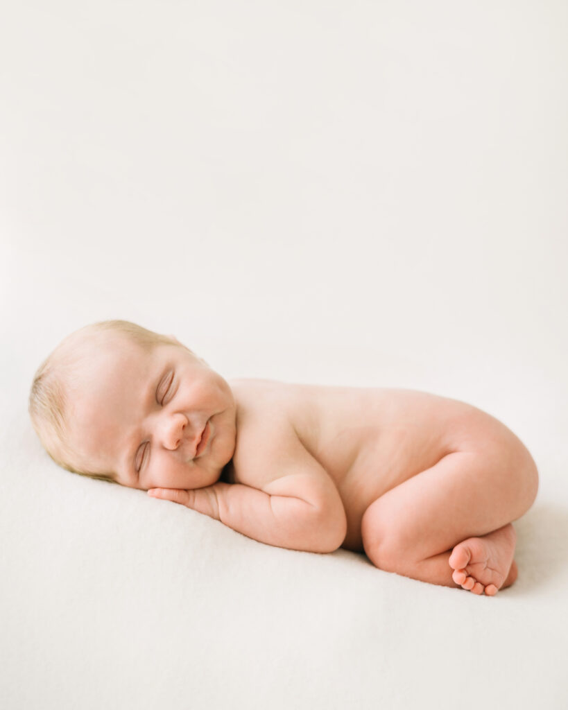 Must-have newborn photos of baby smiling while sleeping during her studio newborn photo session