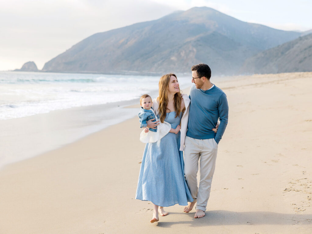 When to book fall family photos: family laughing together on a Malibu beach during golden hour.