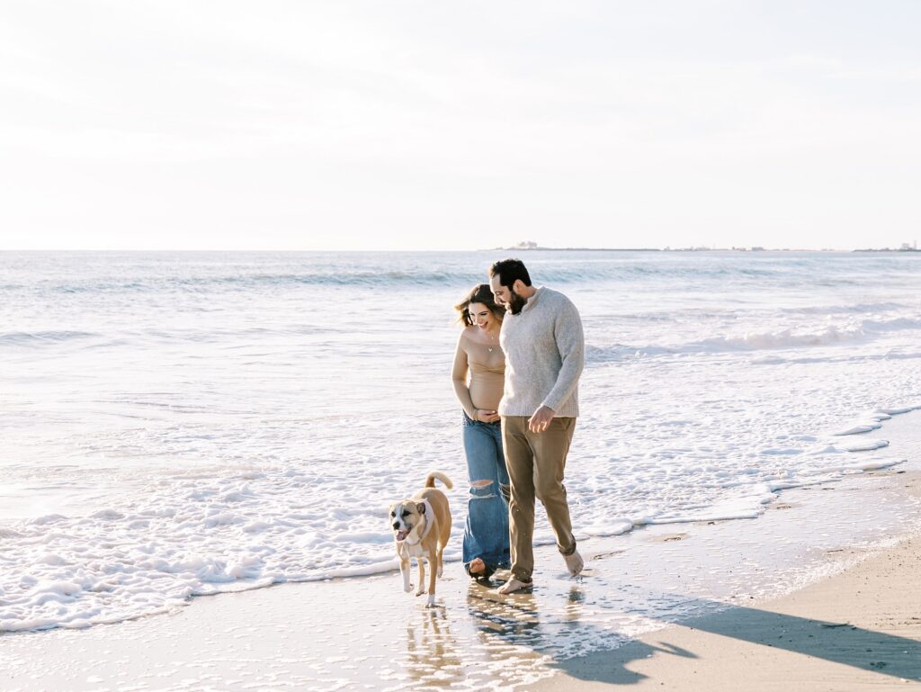 Natural Malibu maternity photos of expecting parents walking together on the beach during golden hour