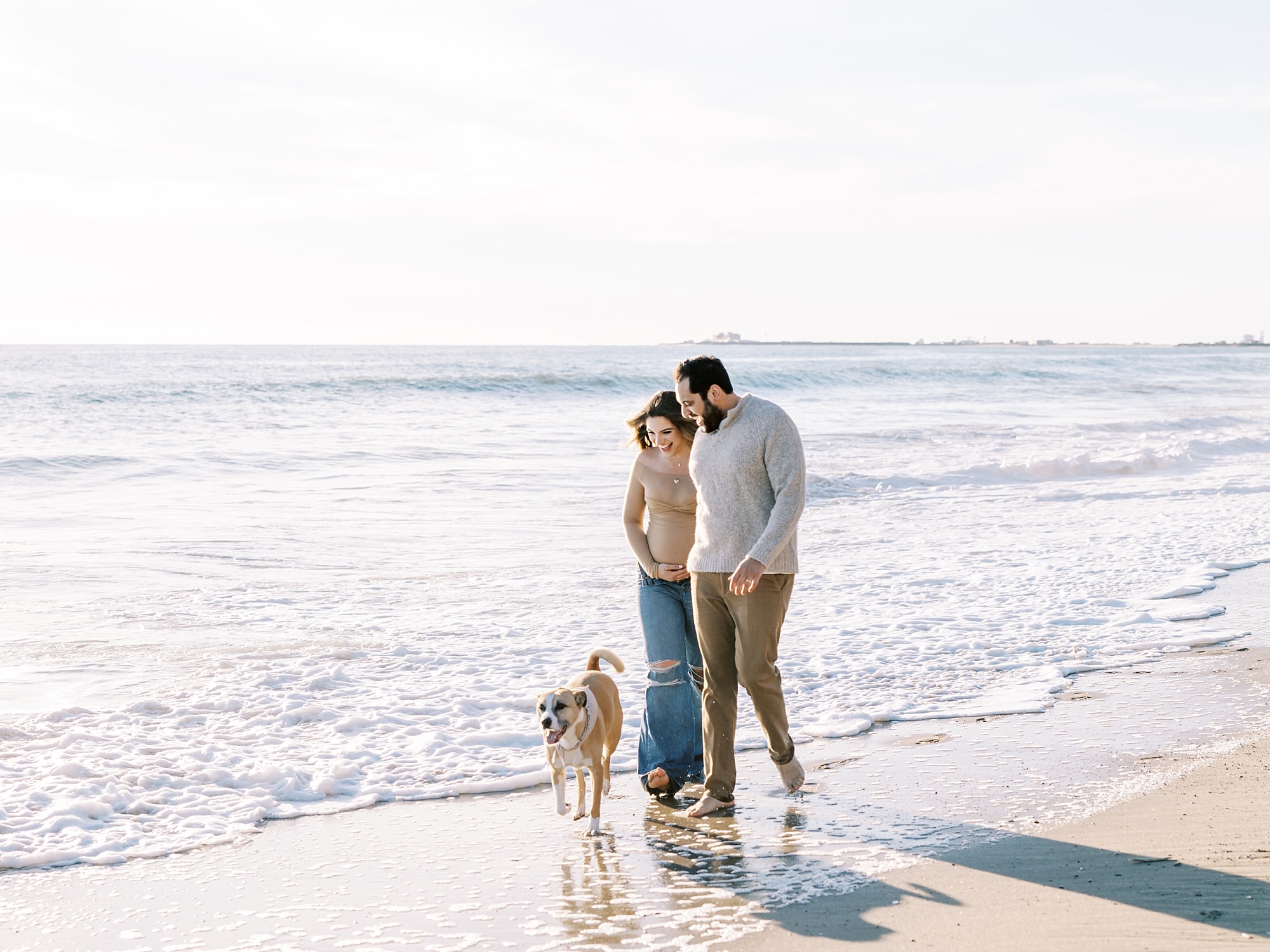 Natural Malibu maternity photos of expecting parents walking together on the beach during golden hour