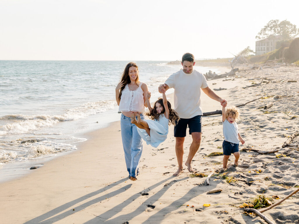 Family playing together on the beach, showing how it's ok if kids won't cooperate during family photos to create natural, playful images
