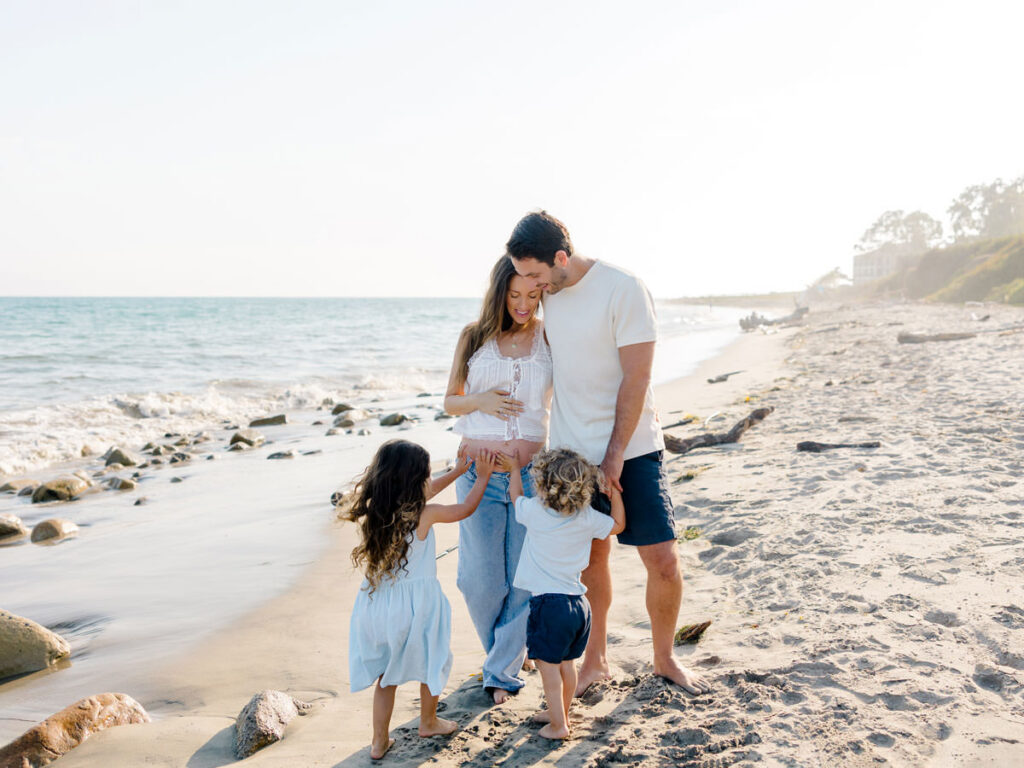 Young children playing with their parents during natural family photos at the beach