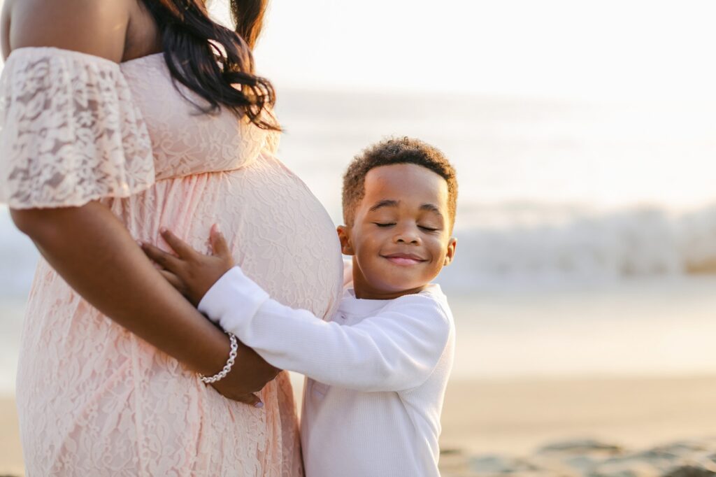 Expecting mother and young son sharing a quiet moment together at the beach